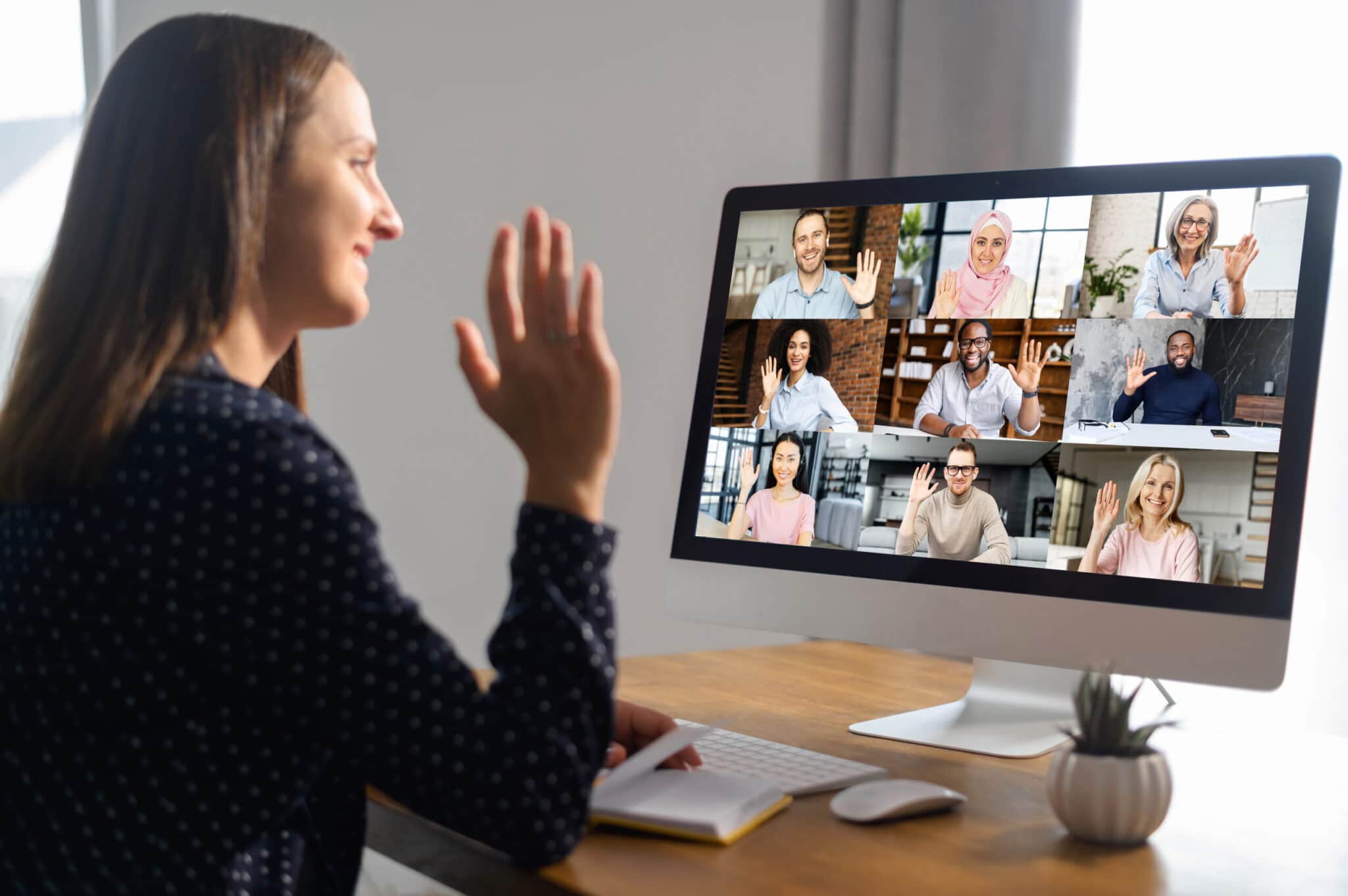Online video discussion with many people together. Young woman sits in front of laptop with many icons, photo profiles of people on screen. App for video meeting with diverse team